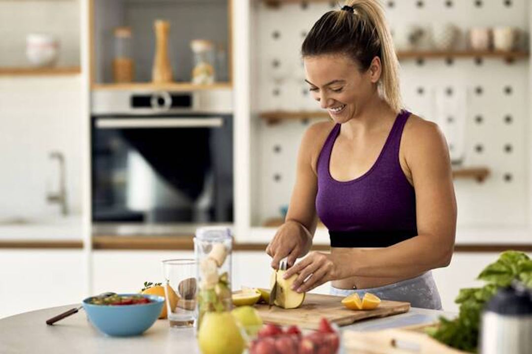 Une femme qui prépare son petit déjeuner riche en multivitamines