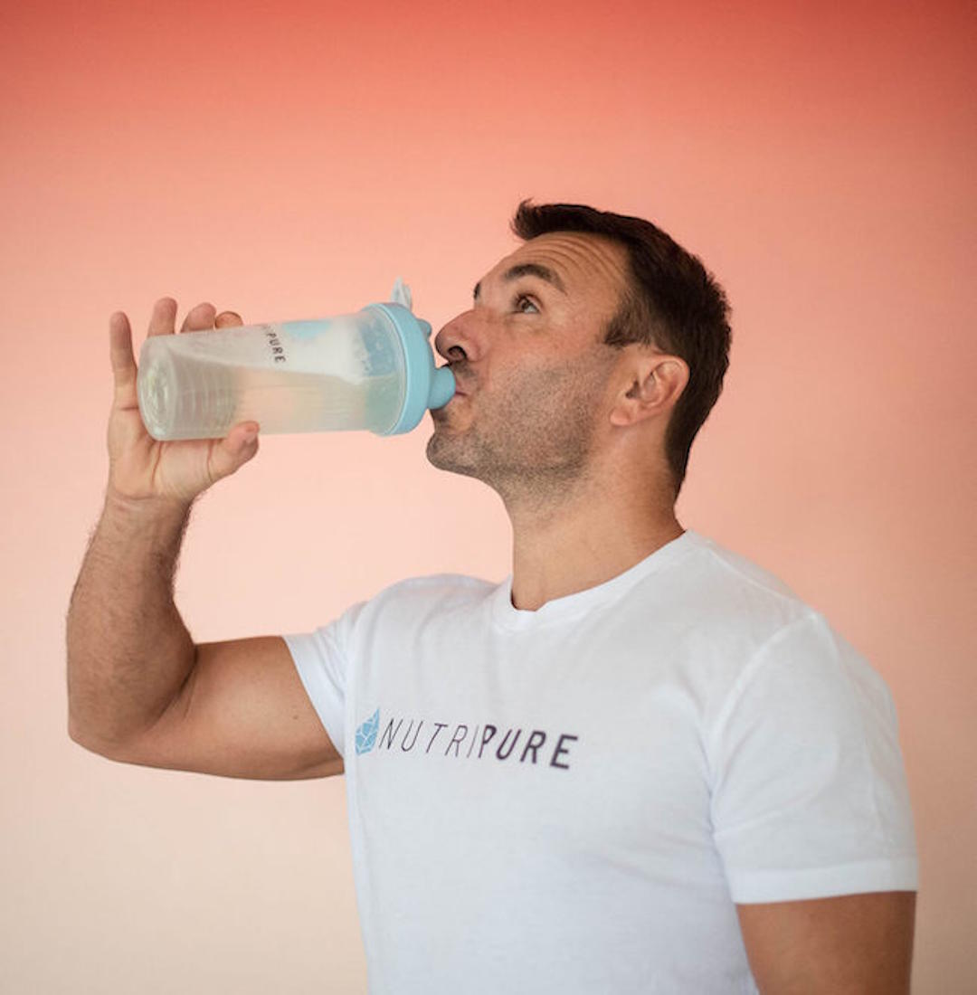 Un homme qui boit de l'eau dans une gourde Nutripure