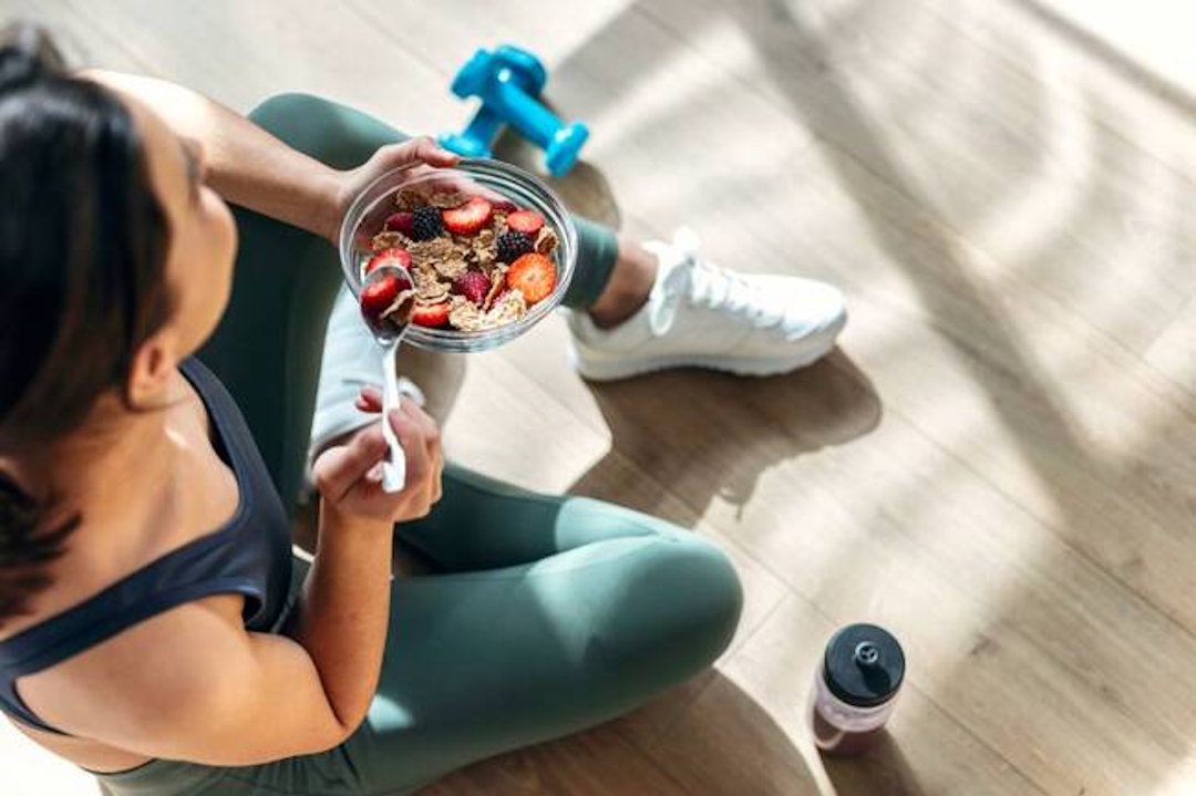 Une femme sportive qui mange un plat avec des aliments riches en vitamine D