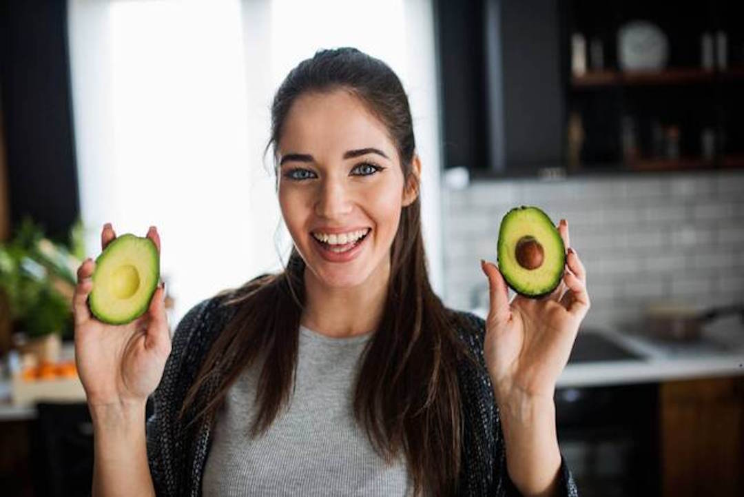Une femme qui ange un avocat pour l'oméga 3