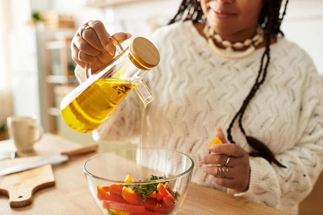 Une femme qui verse de l'Huile de noix dans une salade