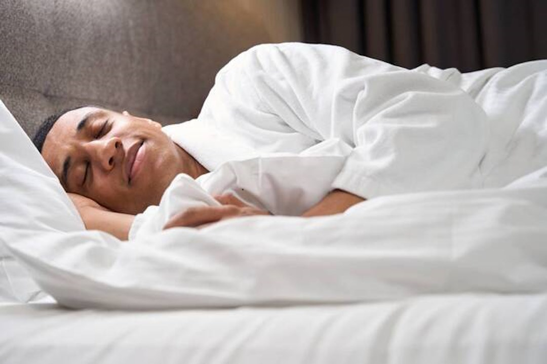 Un homme qui dort dans des draps blancs