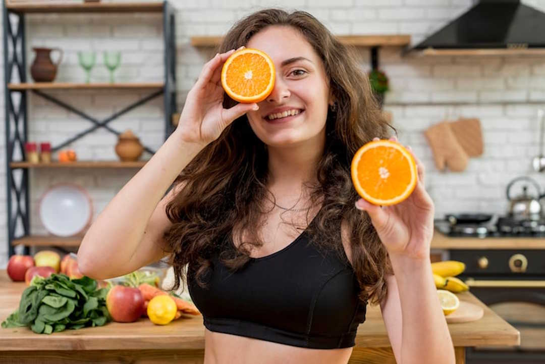 Une femme qui tient de l'orange, riche en vitamine C