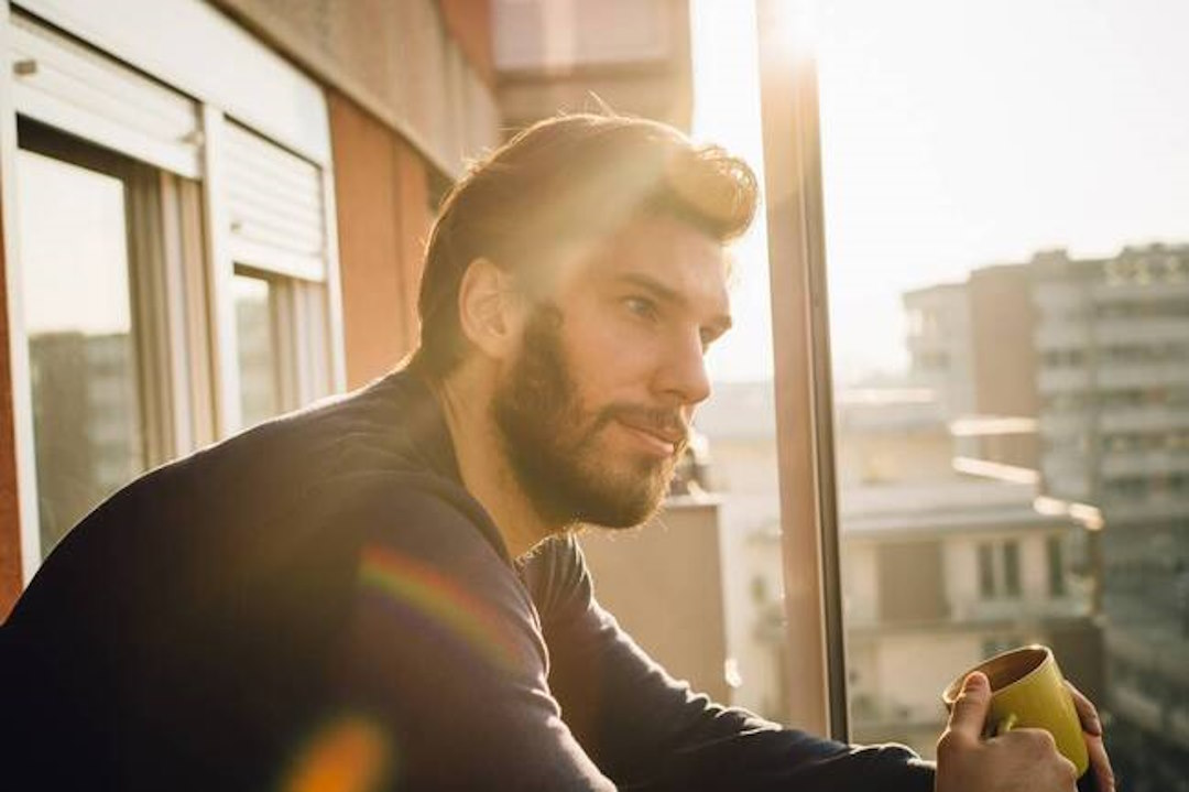 Un homme qui prend son café sur le balcon et profite un peu du soleil