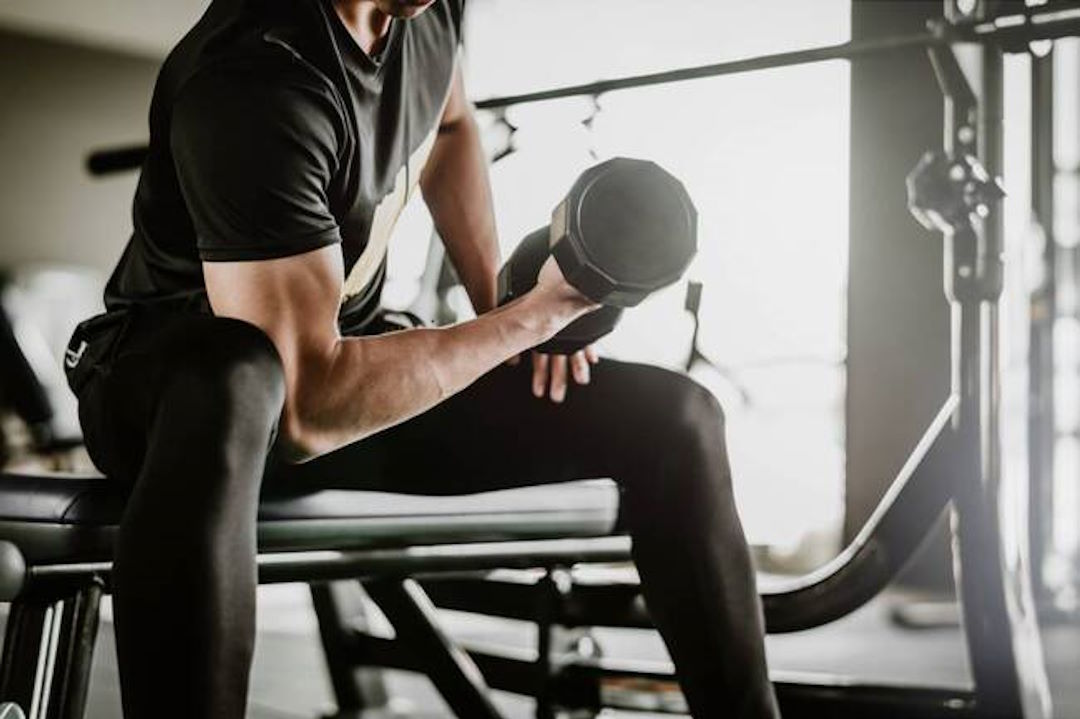 Un homme qui fait du curl biceps