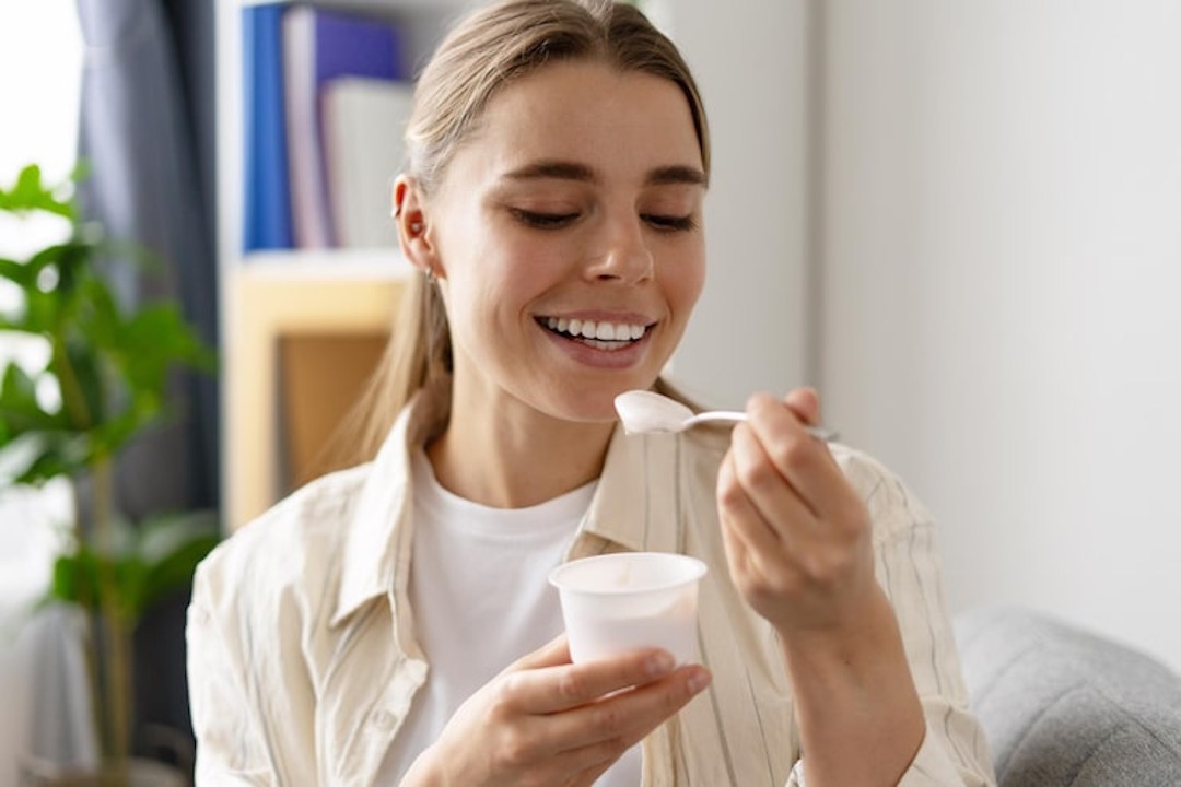 Une personne qui mange un yaourt pour la vitamine B12